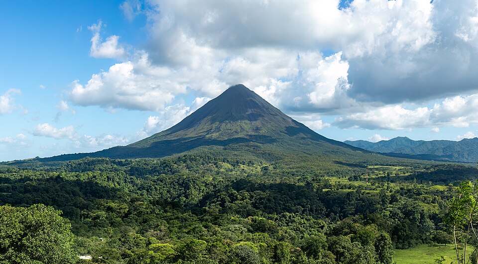 Vulcão Arenal com mata fechada ao redor e nuvens no céu, na Costa Rica